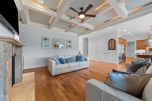 living area with ceiling fan, a premium fireplace, baseboards, ornamental molding, and coffered ceiling