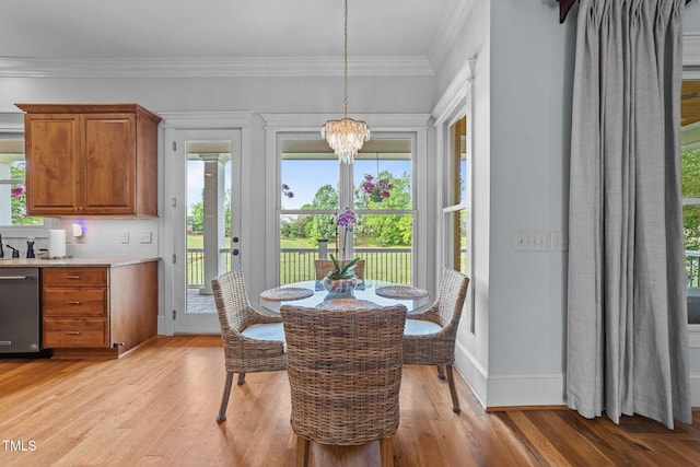 dining area featuring baseboards, ornamental molding, light wood finished floors, and a notable chandelier