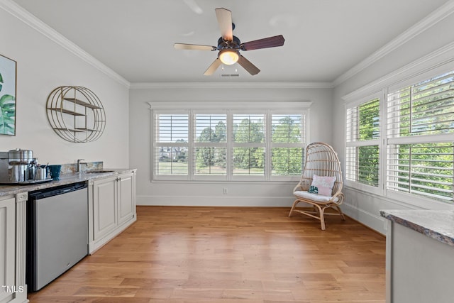 interior space featuring ceiling fan, visible vents, light wood-type flooring, baseboards, and ornamental molding