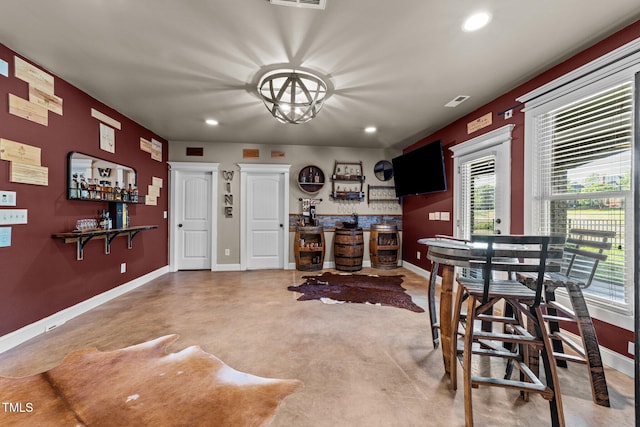 dining area featuring bar, visible vents, baseboards, concrete floors, and recessed lighting