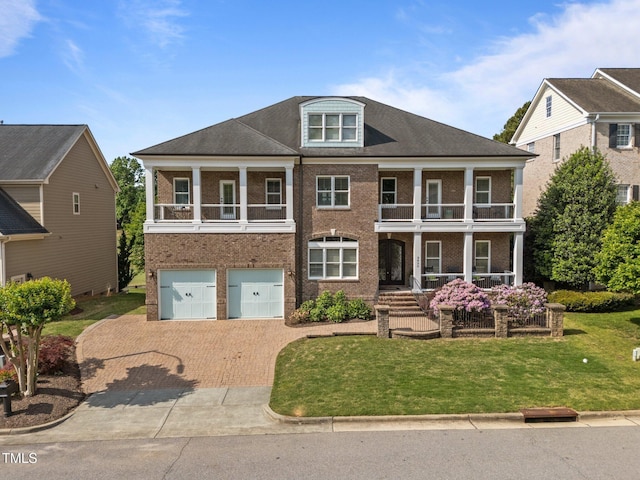 view of front of property featuring a porch, a front yard, brick siding, decorative driveway, and a balcony
