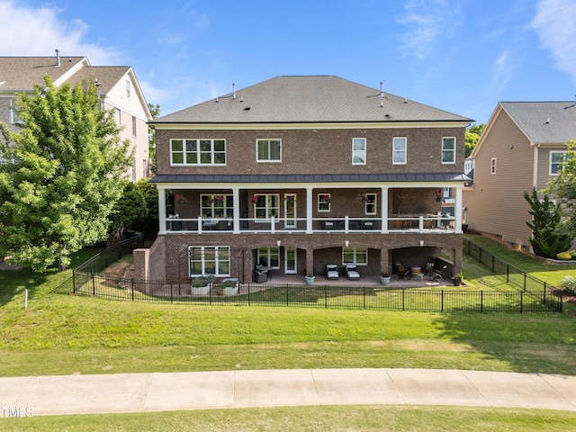 back of house with a standing seam roof, a yard, a patio area, and brick siding