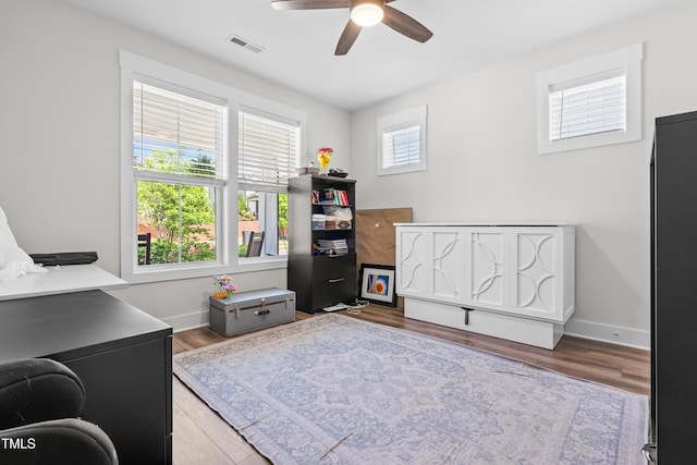 interior space featuring a ceiling fan, baseboards, visible vents, and wood finished floors