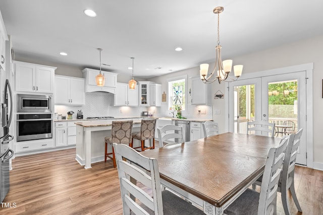 dining area featuring an inviting chandelier, french doors, recessed lighting, and light wood-style flooring