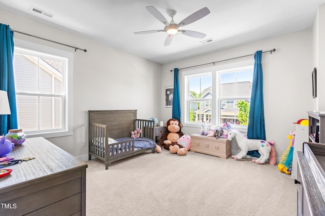 carpeted bedroom with a ceiling fan and visible vents