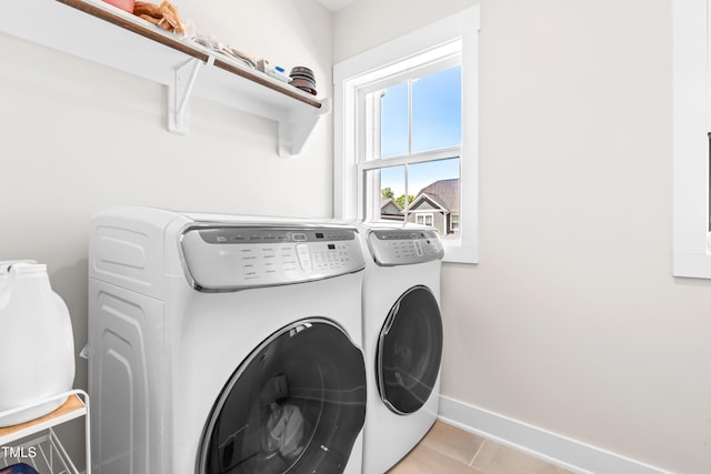 clothes washing area with laundry area, baseboards, light tile patterned floors, and separate washer and dryer