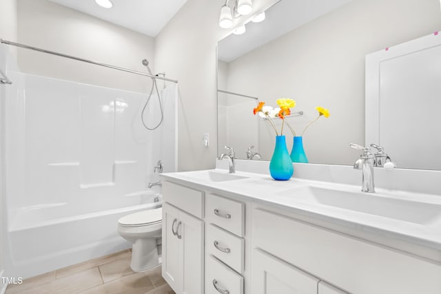 bathroom with double vanity, a sink, tile patterned floors, and toilet