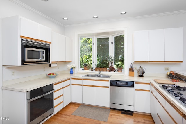 19 Oak Dr, Durham, NC 27707 - kitchen featuring a sink, light wood-style flooring, stainless steel appliances, white cabinetry, and ornamental molding