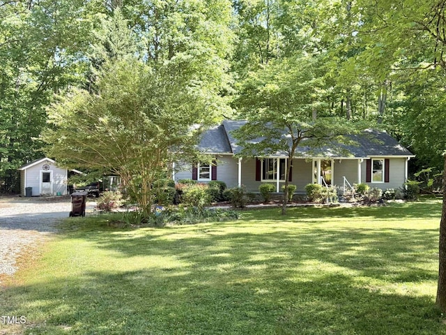 ranch-style home featuring an outbuilding, a front lawn, covered porch, and a shed