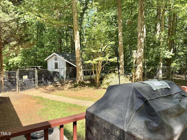 view of yard with an outdoor structure, fence, a storage shed, and a gate
