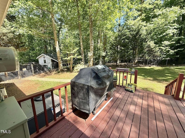 wooden terrace with a fenced backyard, a yard, and area for grilling