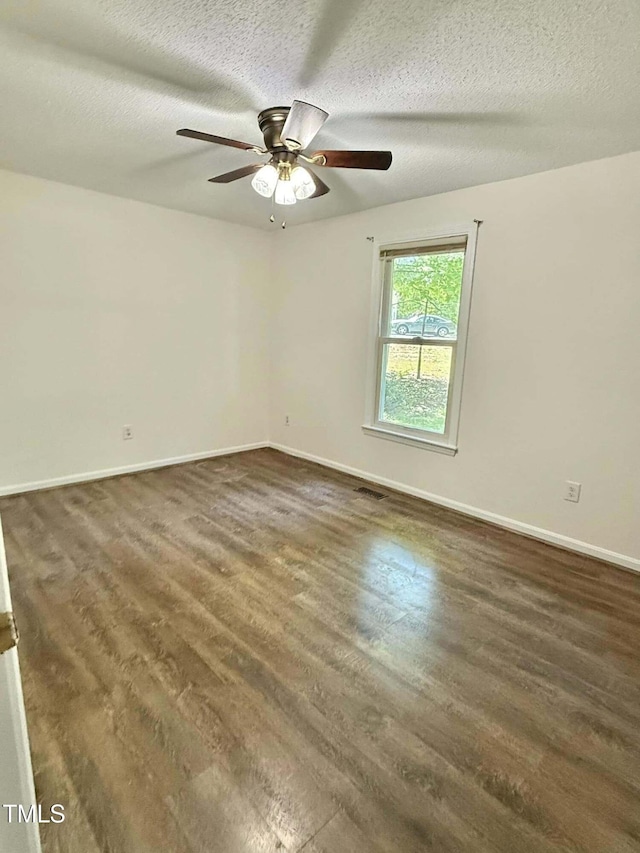 empty room featuring a ceiling fan, baseboards, a textured ceiling, and dark wood-type flooring