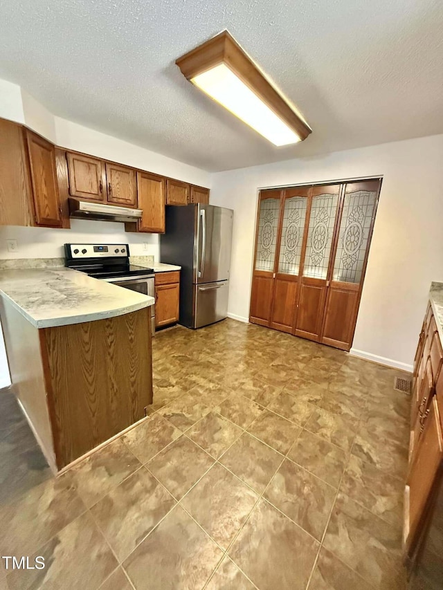 kitchen with appliances with stainless steel finishes, light countertops, brown cabinetry, a peninsula, and under cabinet range hood