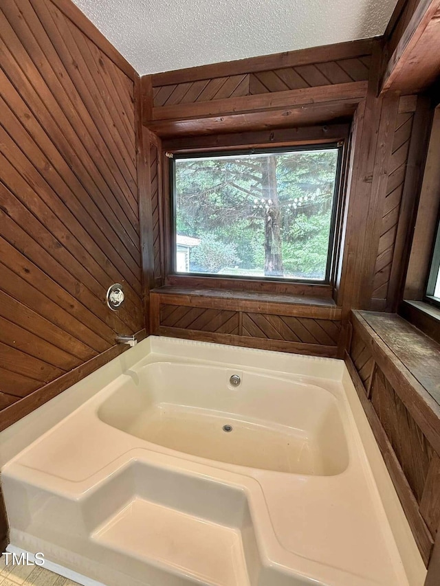 full bathroom with a garden tub, a textured ceiling, and wooden walls