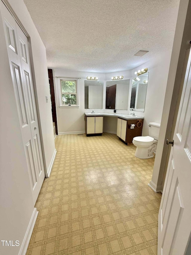 full bathroom with vanity, toilet, a textured ceiling, tile patterned floors, and baseboards