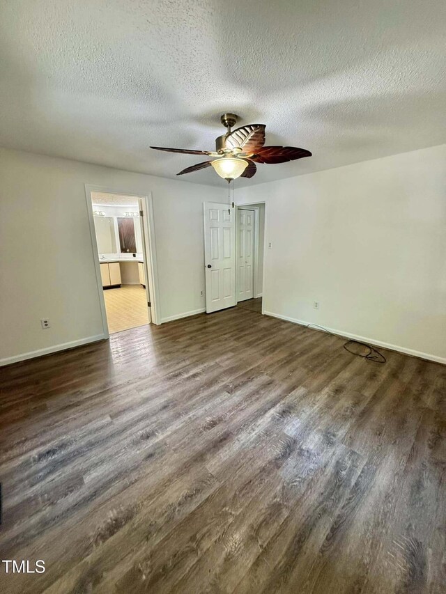 spare room with baseboards, a ceiling fan, a textured ceiling, and wood finished floors