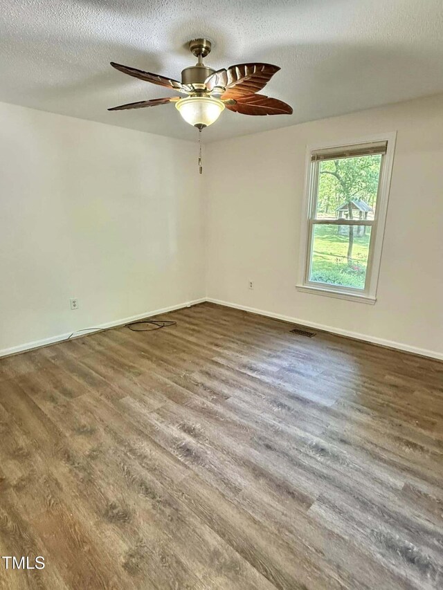 spare room with visible vents, wood finished floors, baseboards, a textured ceiling, and a ceiling fan