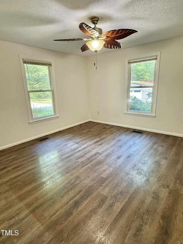 empty room with visible vents, dark wood-type flooring, and a healthy amount of sunlight