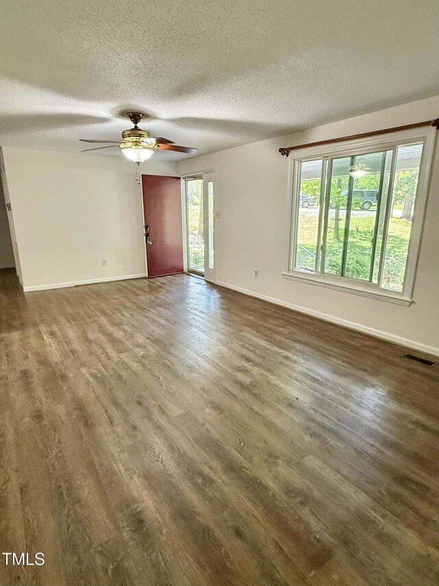 unfurnished living room featuring visible vents, baseboards, and wood finished floors