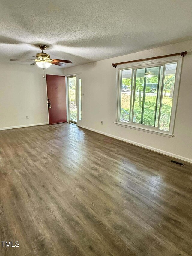 unfurnished living room with baseboards, a wealth of natural light, and dark wood-type flooring