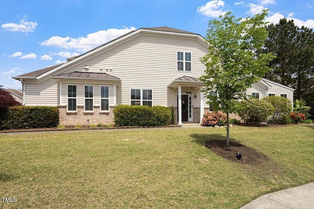 traditional home with brick siding, a standing seam roof, metal roof, and a front lawn