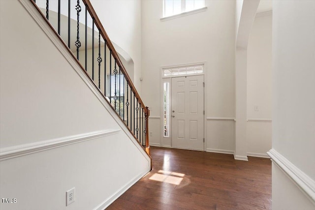 foyer featuring stairs, baseboards, wood finished floors, and a towering ceiling
