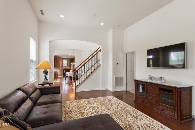 living area with arched walkways, stairs, wood finished floors, and visible vents