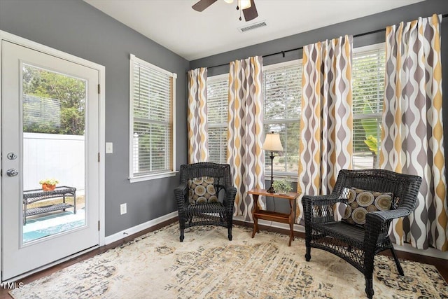 living area with a ceiling fan, visible vents, and plenty of natural light