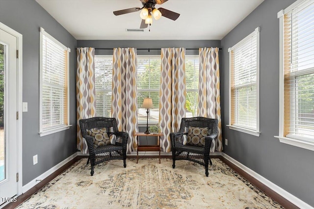 sitting room featuring a ceiling fan, visible vents, plenty of natural light, and wood finished floors