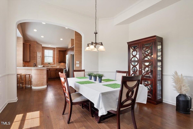 dining area featuring arched walkways, a chandelier, dark wood-style floors, and ornamental molding