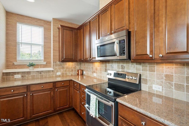 kitchen with light stone counters, brown cabinetry, and stainless steel appliances