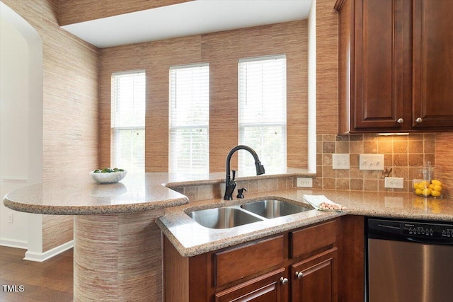 kitchen featuring a sink, a healthy amount of sunlight, light stone countertops, and dishwasher
