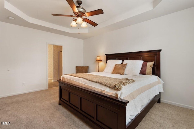 bedroom featuring a ceiling fan, baseboards, light colored carpet, and a raised ceiling