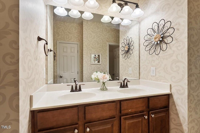 bathroom featuring double vanity, a sink, and wallpapered walls