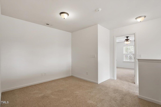 carpeted spare room featuring baseboards, ceiling fan, and visible vents