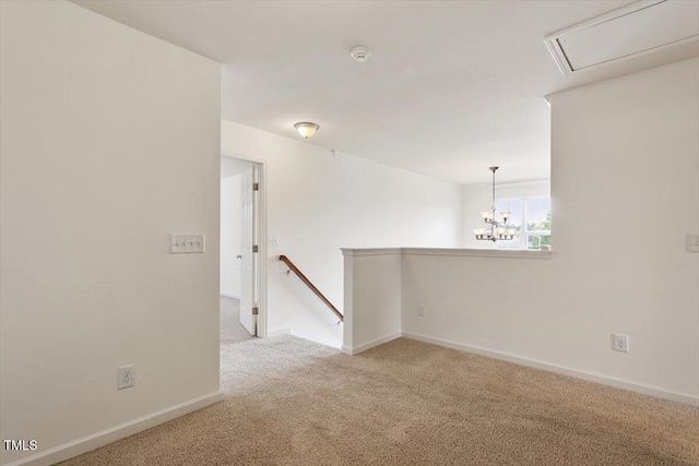 unfurnished room featuring an inviting chandelier, baseboards, carpet flooring, and attic access