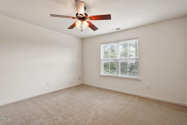 spare room featuring baseboards, a ceiling fan, light colored carpet, and visible vents