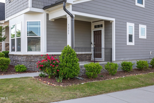 property entrance with a lawn and stone siding