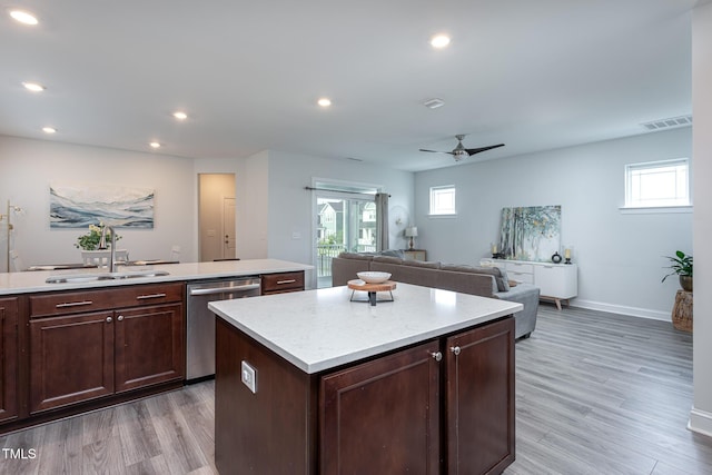 kitchen with a kitchen island, visible vents, stainless steel dishwasher, a sink, and light countertops
