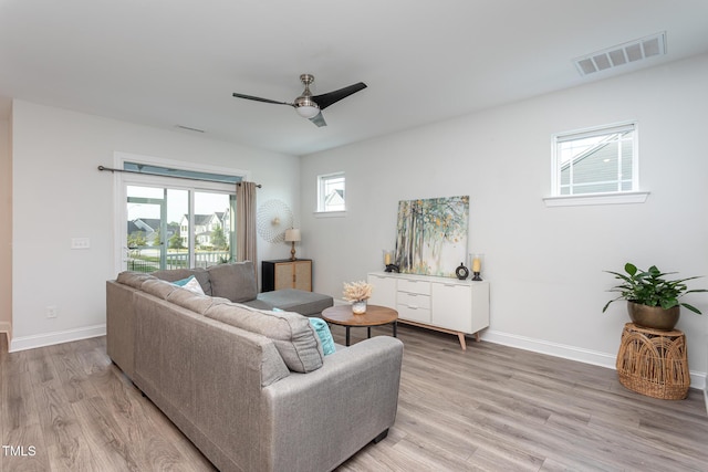 living area featuring ceiling fan, visible vents, baseboards, and light wood-type flooring