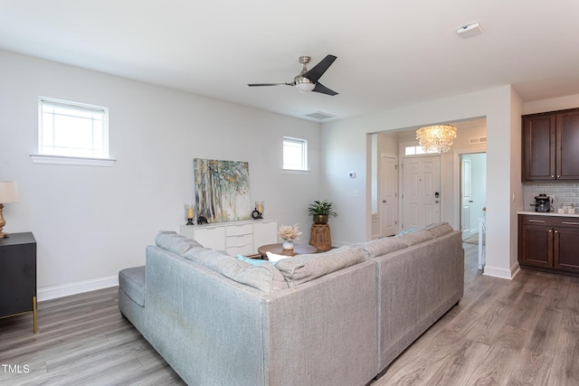 living area with baseboards, ceiling fan with notable chandelier, light wood-type flooring, and visible vents