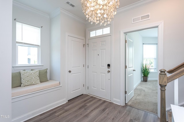 foyer featuring visible vents, crown molding, wood finished floors, and an inviting chandelier