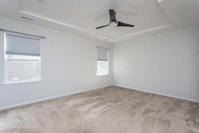spare room featuring a ceiling fan, carpet, a tray ceiling, and visible vents