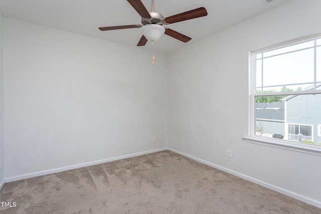 carpeted empty room featuring baseboards and ceiling fan