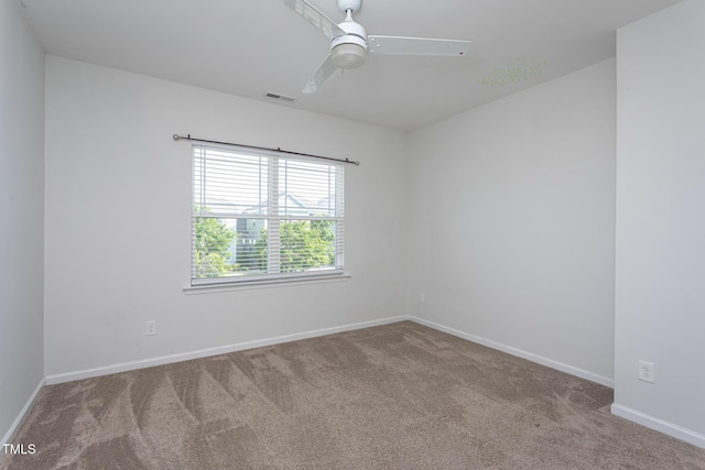carpeted spare room with visible vents, a ceiling fan, and baseboards