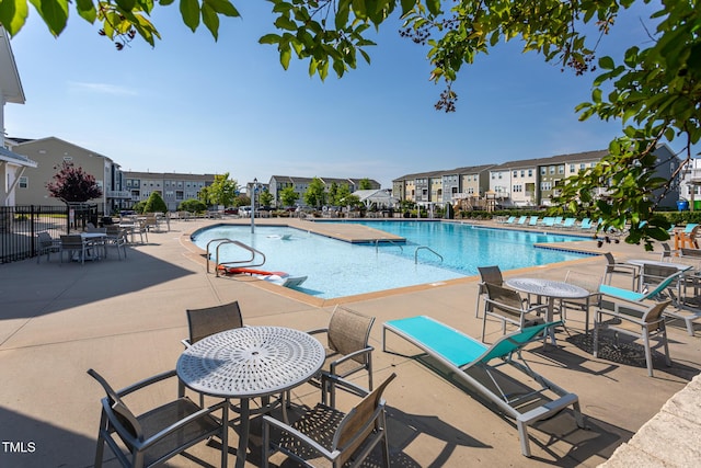community pool with fence, a patio, and a residential view