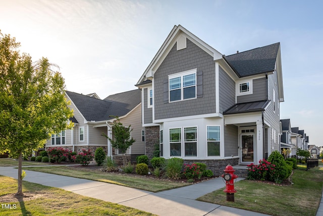 craftsman inspired home featuring fence, stone siding, a front yard, a standing seam roof, and metal roof