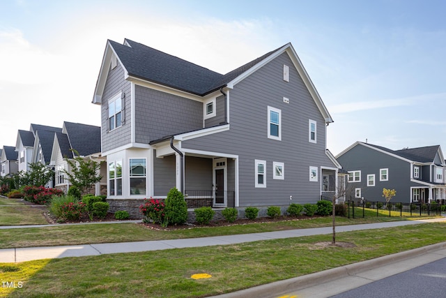 view of front of home featuring a residential view, fence, and a front lawn