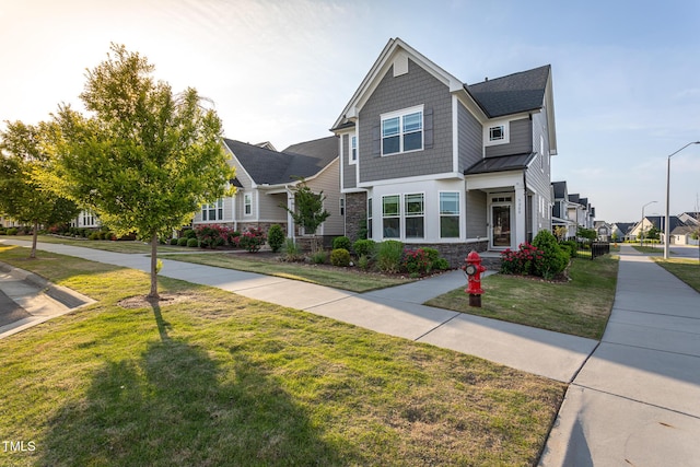 view of front of house featuring a standing seam roof, metal roof, a front lawn, and stone siding