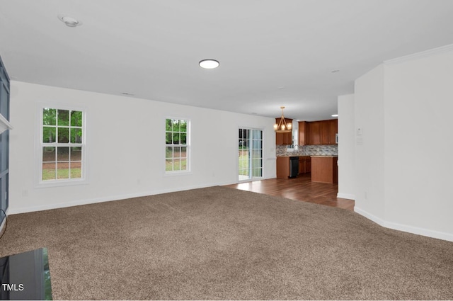 unfurnished living room with baseboards, a fireplace, dark carpet, and a notable chandelier